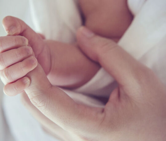 mom cuddling baby's hand