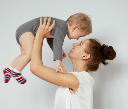 mom holds high her two year old