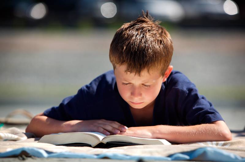 boy reads book outside