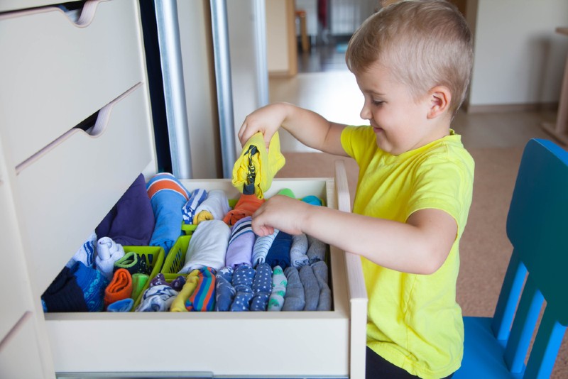 little boy tidies clothes