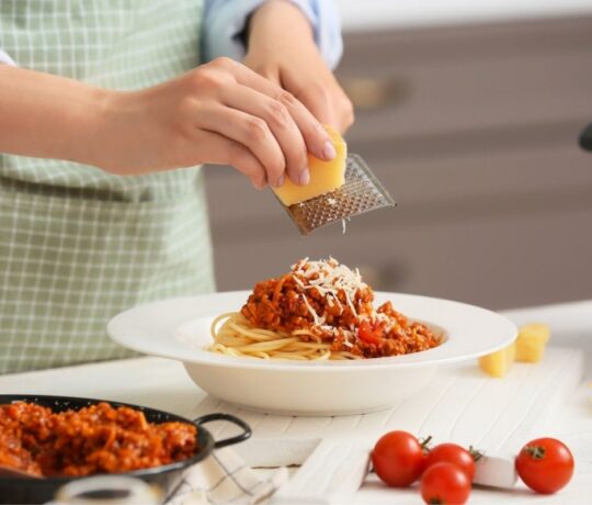 Woman cooking pasta bolognese in kitchen