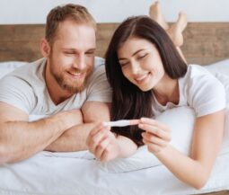 couple with pregnancy test in the bed