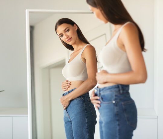 pregnant watching herself in the mirror