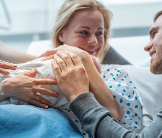 father hugs his baby and his wife after birth