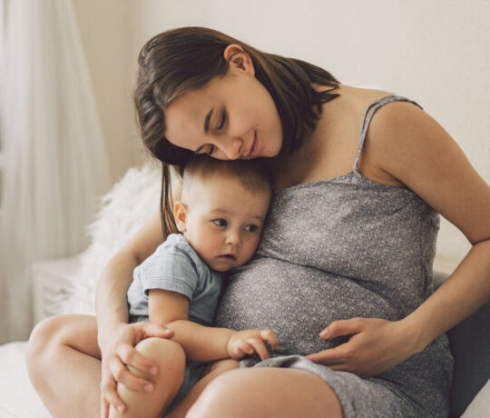pregnant woman hugs her baby