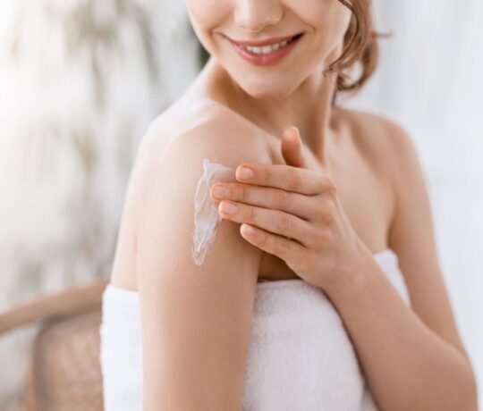 woman applies cream on her shoulder