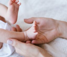 hand touching baby's leg